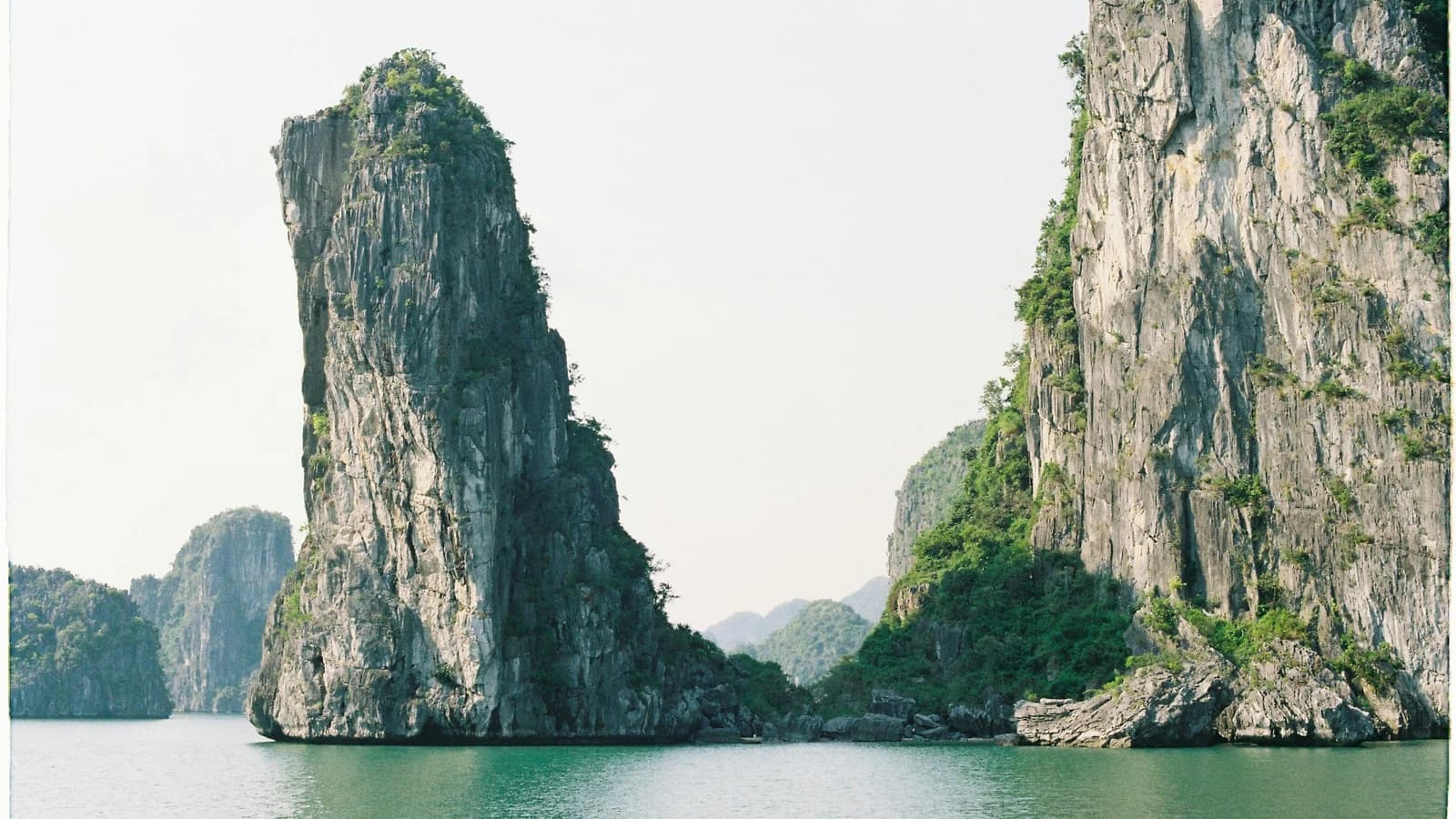 Towering limestone islands rising from emerald waters in Ha Long Bay, Vietnam, under clear blue skies